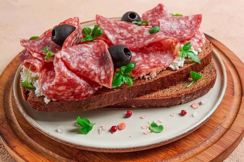 Sandwich, grain bread, with cream cheese and salami, black olives, micro-greens, top view,