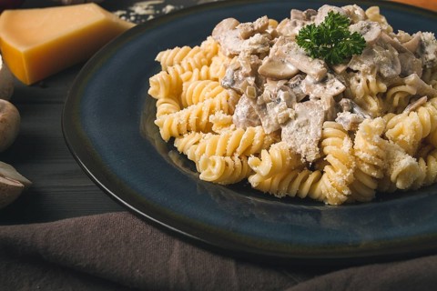 Fusilli pasta, with champignons in cream sauce, top view, with ingredients, on a wooden table, no