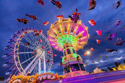 Chain carousel and Ferris wheel in the evening. 177th Cannstatter Volksfest at the Cannstatter