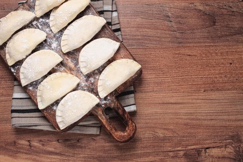 Traditional Polish dish, dumplings, raw, frozen, on a cutting board, wooden table, top view, no