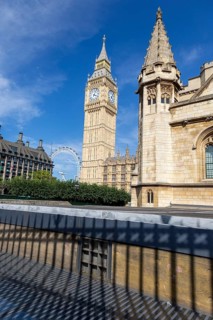Big Ben and another historic building under a clear blue sky in London, United Kingdom United