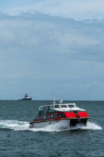 Dune ferry full speed ahead to the offshore island of Helgoland, tugboat on the horizon, North Sea,
