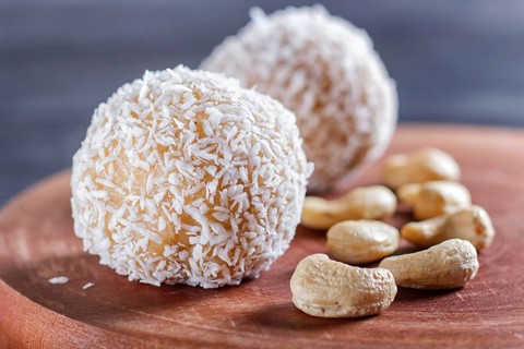 Energy balls cakes with coconut and cashew on wooden board on black background. selective focus,