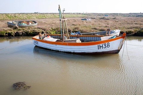 Small fishing boats moored in tidal inlet on the River Alde at Slaughden, Aldeburgh, Suffolk,