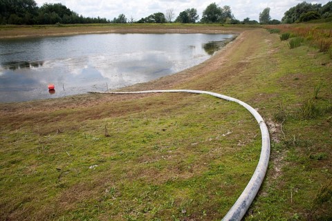 Irrigation pipe water reservoir lake at low level in summer Sutton, Suffolk, England, UK