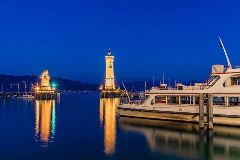 Bavarian Lion, the lighthouse and an excursion boat in the harbour at the blue hour, Lindau Island,