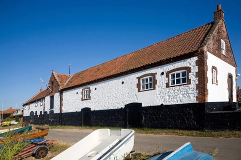 Whitewashed boathouse at the coastal village of Burnham Overy Staithe, north Norfolk coast,