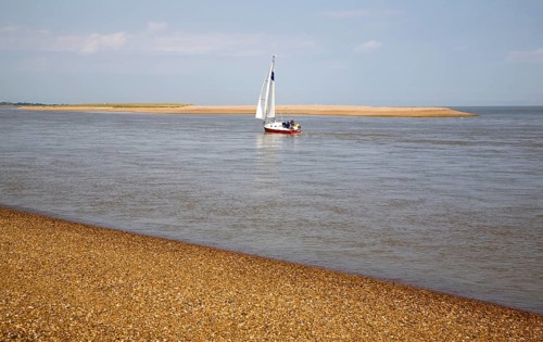Sailing boat at the mouth of the River Ore at the tip of Orford Ness shingle spit, North Weir