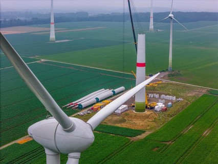 Erection of the tower of a wind power plant in a wind farm near Issum, 9 older wind turbines from