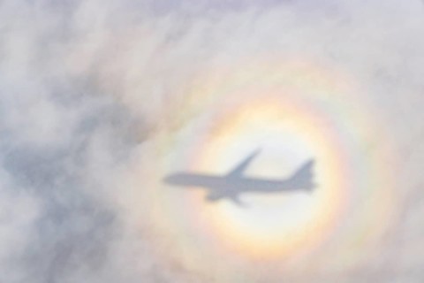 An aeroplane casts a shadow on a cloud, silhouette, halo rainbow. Germany