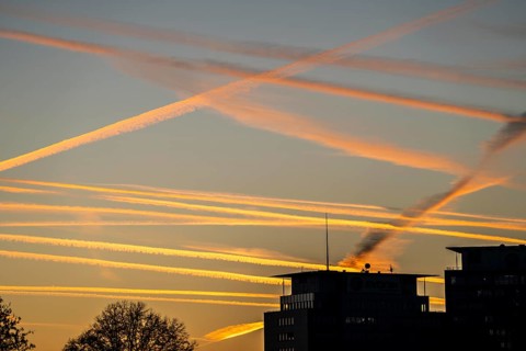 Condensation trails from aircraft flying at high altitude, evening sky, after sunset