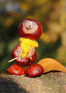 Chestnut figure with yellow scarf and leaves on tree trunk, North Rhine-Westphalia, Germany, Europe