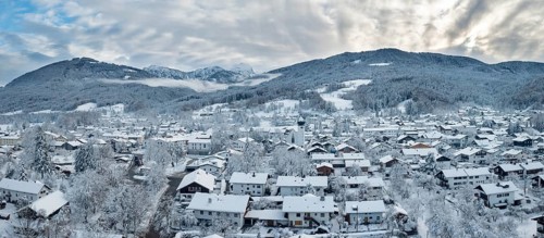 Snow-covered village in a mountain landscape under a cloudy sky, Bad Feilnbach
