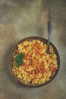 Risotto with shrimp, in a bowl, on a textured surface, with a side dish of fresh coriander,