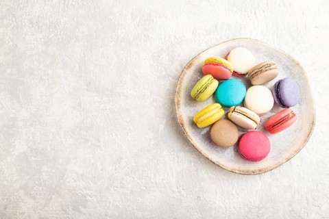Multicolored macaroons on ceramic plate on gray concrete background. top view, copy space, still