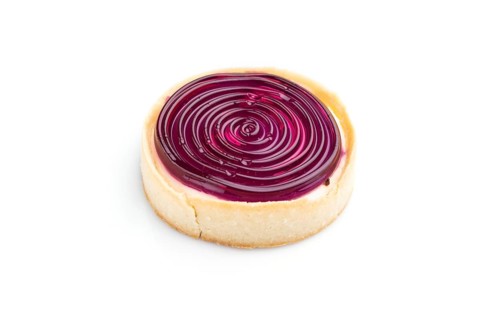 Single sweet tartlet with jelly and milk cream isolated on white background. Side view, close up