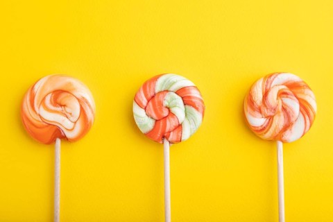 Three lollipop candies on yellow pastel background. copy space, top view, flat lay