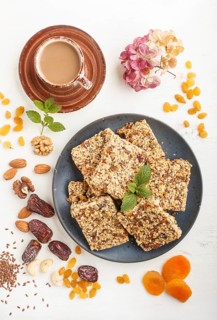Homemade granola from oat flakes, dates, dried apricots, raisins, nuts in blue ceramic plate with a