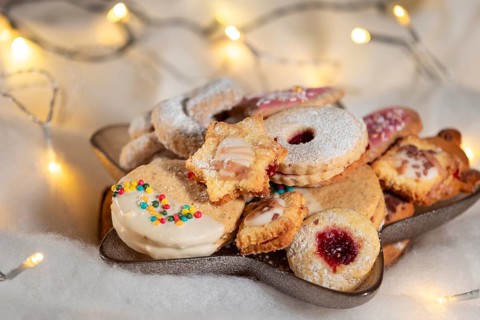 A plate full of Christmas biscuits with colourful sprinkles and soft lighting
