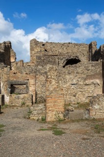 Remnants of old terracotta brick and stone wall structures with rectangular and arched openings at