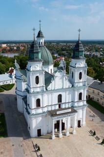 Large baroque church with white facades and green towers in a cityscape in sunny weather, Basilica