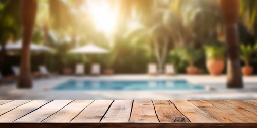 Empty wooden board with tropical resort swimming pool and palm trees in blurry background. KI