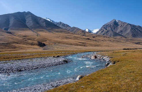 Blue river in the Burkhan valley, mountain landscape with glaciated peaks and golden meadows,