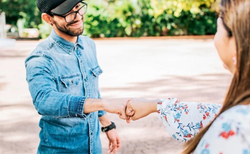 Young man and girl shaking fists in the street. A guy and girl shaking hands on the street. Two