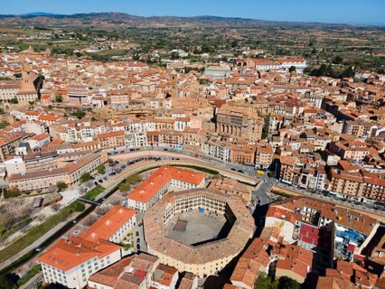 Aerial view of a historic town with tiled roofs and a central square in the middle of a hilly