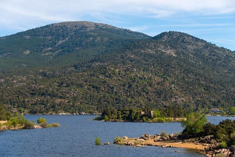 An idyllic lake in the middle of a wooded mountain landscape with small islands and calm waters,