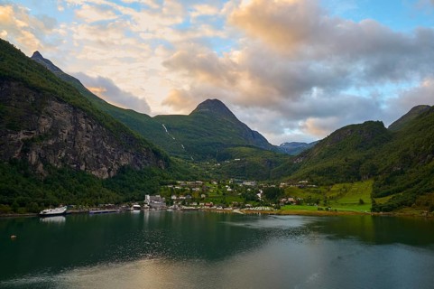 Geiranger with fjord landscape with mountains embedded in nature, covered by dramatic clouds,