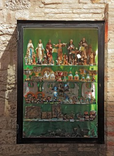 Shop window with figures of saints, devotional objects, in the historic centre of Assisi, Umbria,