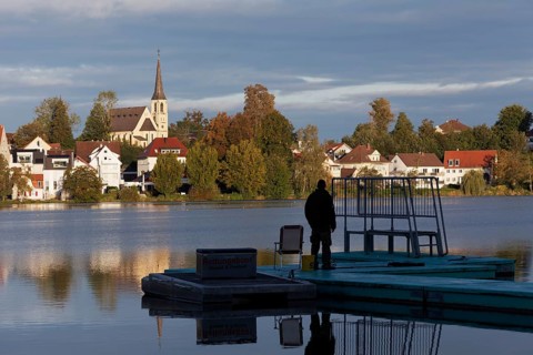 View over the town lake to Bad forest lake, man on a footbridge, morning light, Bad forest lake,