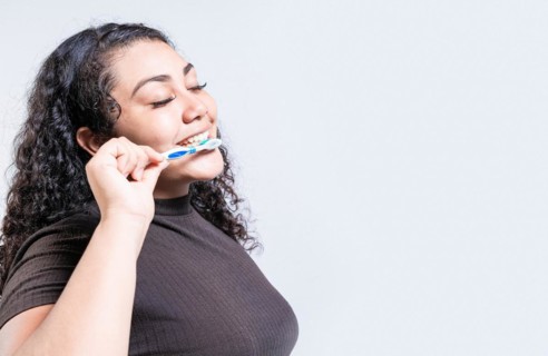 Face of young woman brushing teeth isolated. Oral and dental smile concept. Smiling woman brushing