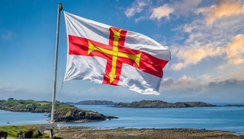 The flag of the Isle of Guernsey, Great Britain, flutters in the wind