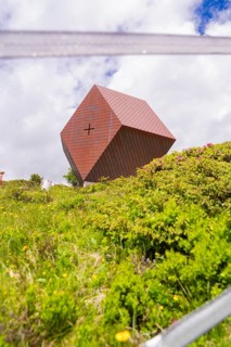 A modern metal chapel sits on a green hill under a cloudy sky, Penken, Zillertal, Austria, Europe