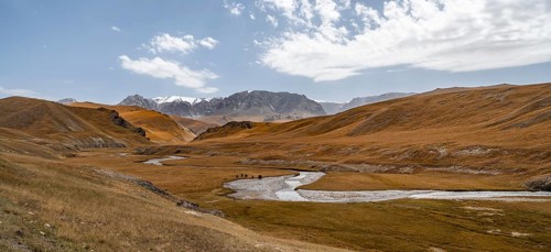 River Kol Suu winds through a mountain valley with hills of yellow grass, Naryn Province,