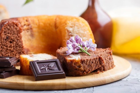 Cakes with raisins and chocolate and a cup of coffee. lilac flowers on a gray concrete background,