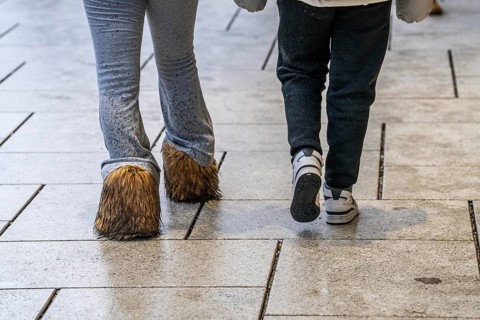 2 woman walking in the rain, one woman wears boots with long fur, wet, dirty, water splashes on her