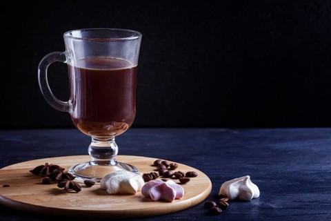 Glass cup of coffee with meringues on a wooden board on a black background. close up, copy space