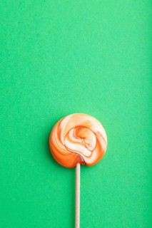 Single lollipop candy on green pastel background. copy space, top view, flat lay