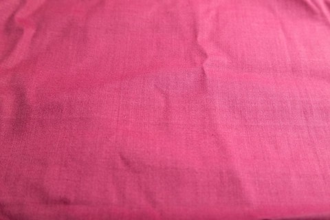 Fragment of smooth cotton purple tissue. Side view, natural textile background and texture