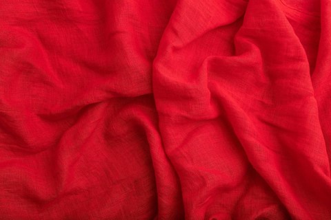 Fragment of red linen tissue. Top view, natural textile background and texture. wave concept,