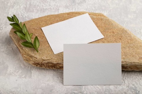 White paper business card, mockup with natural stone and boxwood branch on gray concrete background