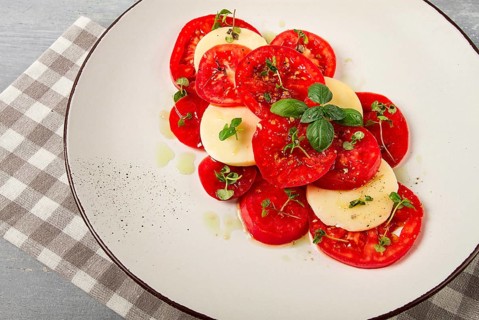 Caprese salad, Italian traditional dish, tomatoes with mozzarella cheese, basil and spices, top