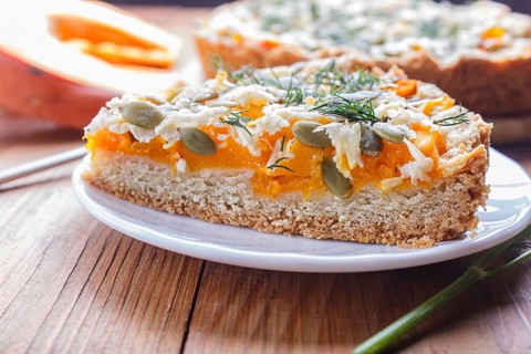A piece of sweet pumpkin pie with cheese and dill on brown wooden background. close up