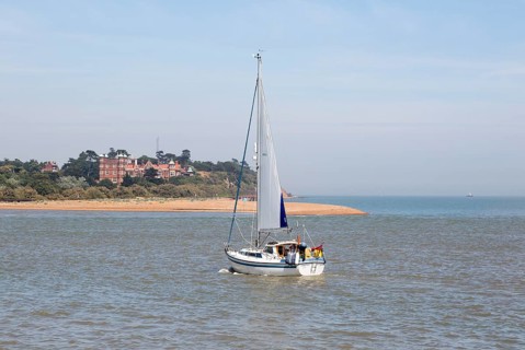 Sailing boat yacht in channel at mouth of River Deben estuary view Felixstowe Ferry to Bawdsey