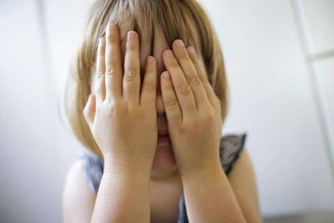 Symbolic photo on the subject of fear in children (posed scene) . A little girl holds her hands in