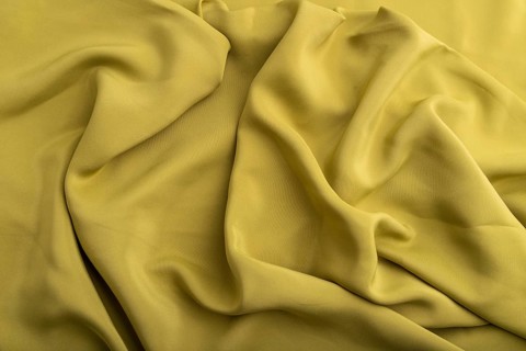Fragment of green olive silk tissue. Top view, natural textile background and texture. wave