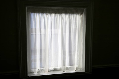 Net curtain in window of dark room letting in light